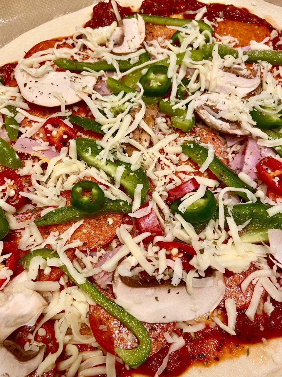 Raw pizza with cheese, peppers, pepperoni and chilli