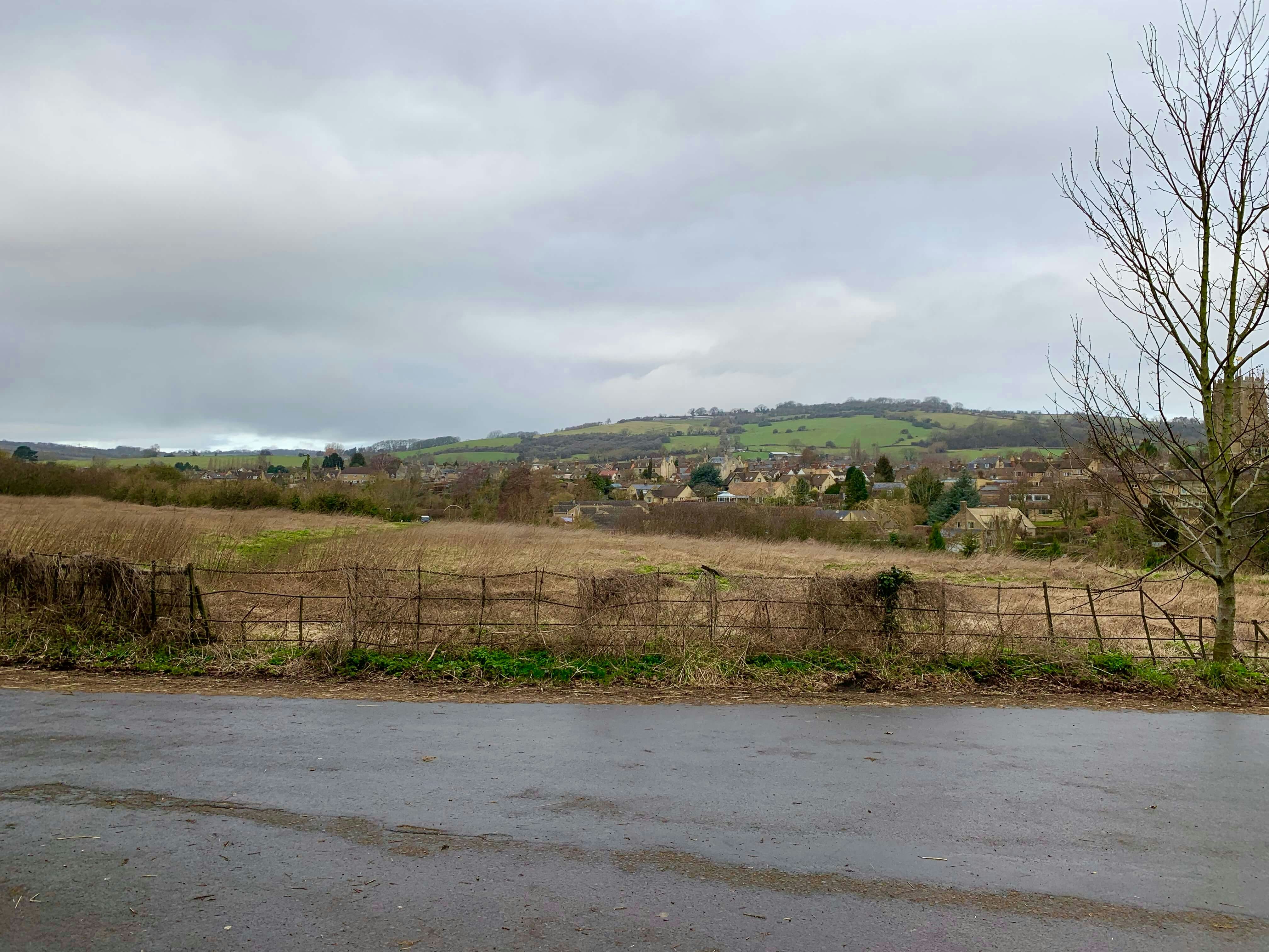 Rolling Cotswolds countryside with a small town in the distance