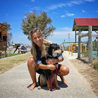 A Kelpie X dog is cuddled by its female owner